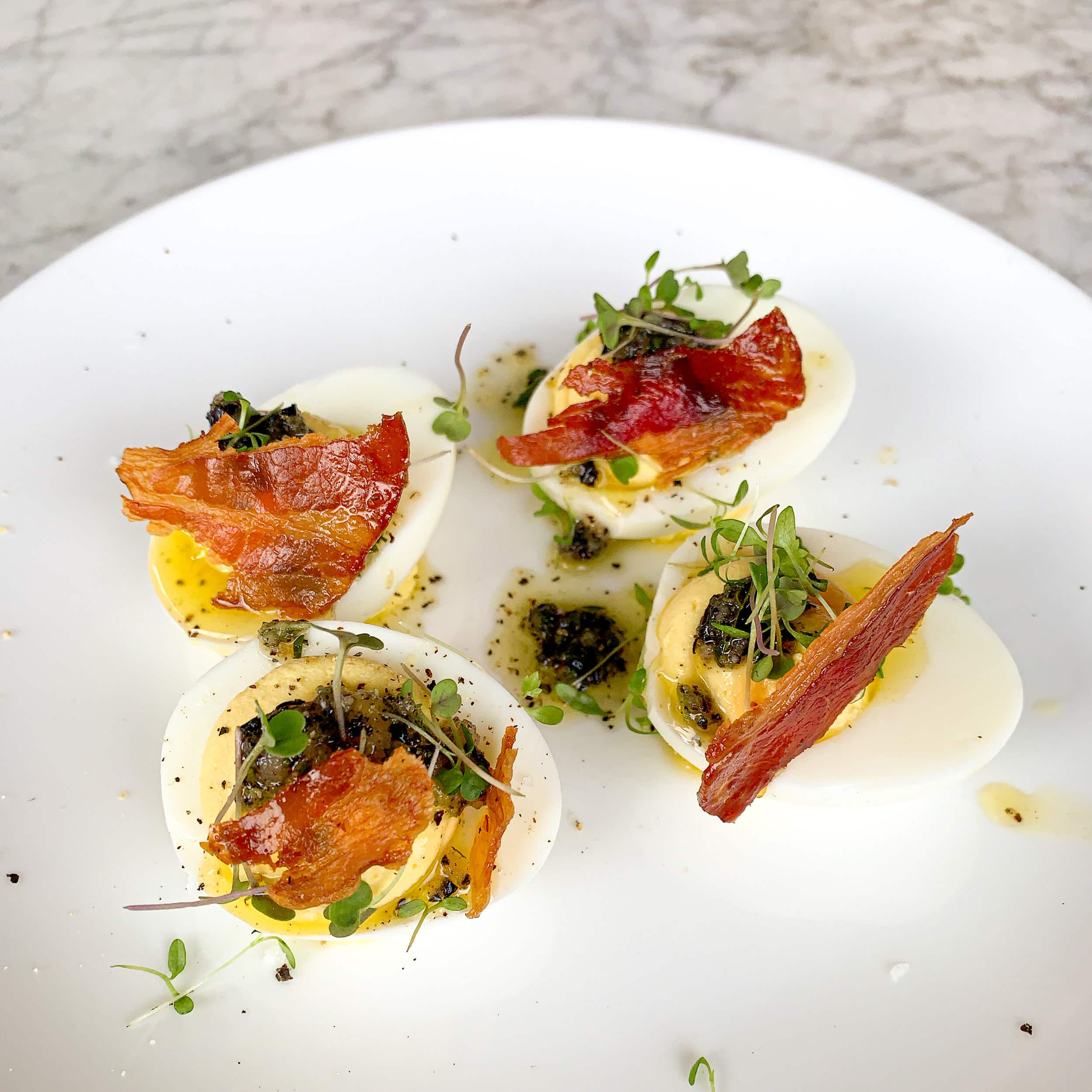 Deviled eggs with black truffle, crispy pancetta, and baby celery at Launderette in East Austin