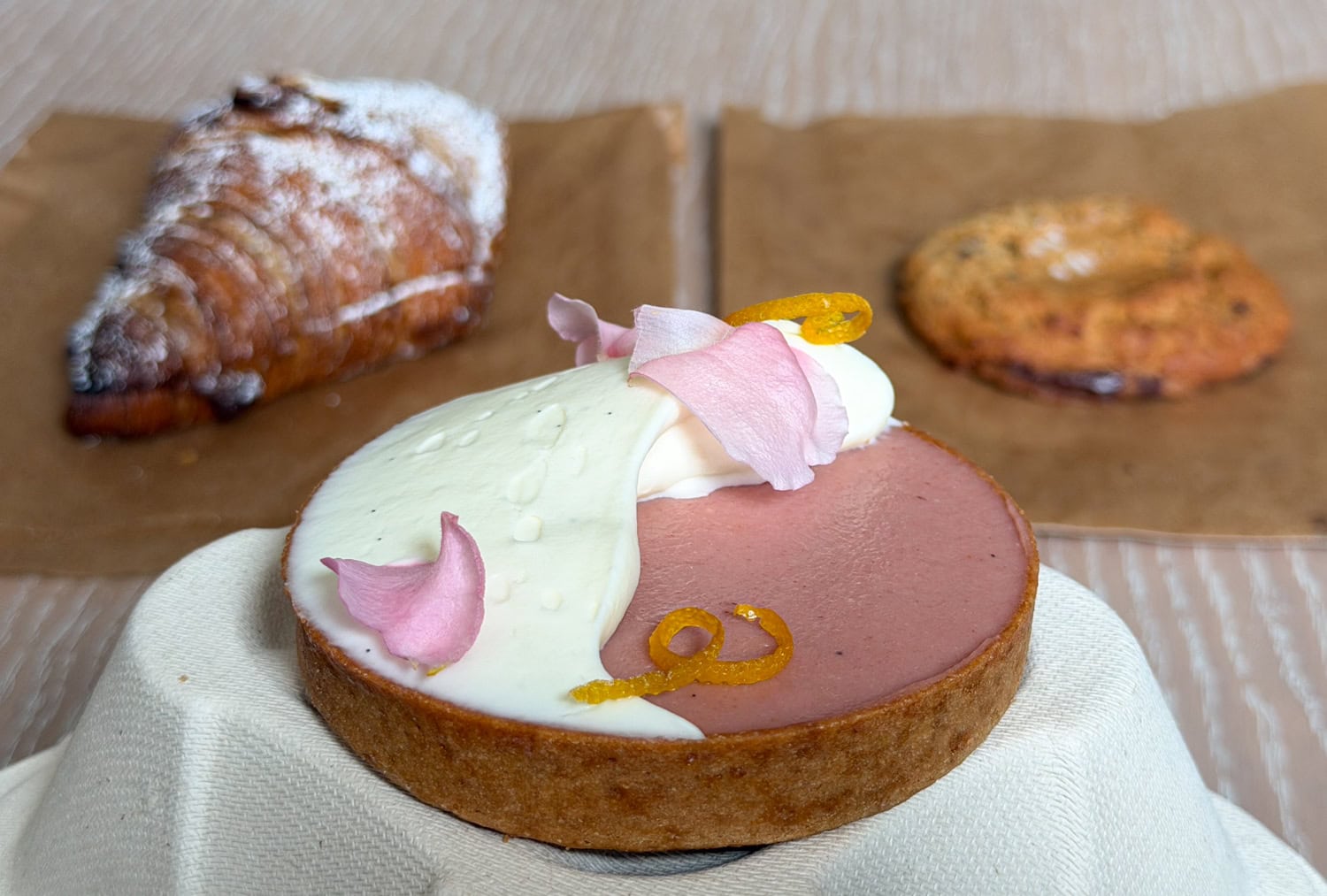 Signature guava tart at Sol Bakery in San Francisco with cream, rose petals, and candied orange zest.