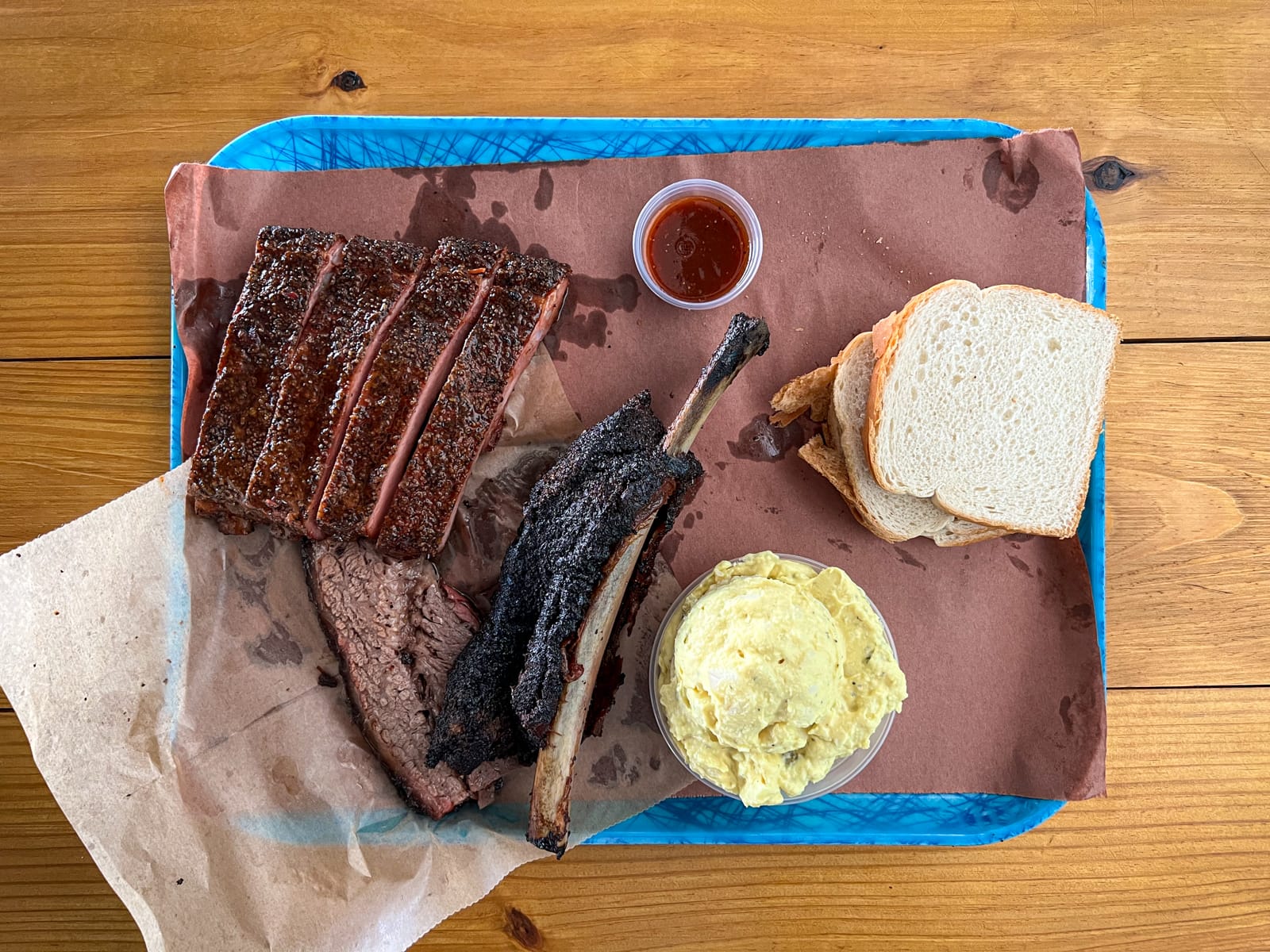 Pork ribs, beef rib, brisket, potato salad, and bread at Franklin Barbecue in East Austin