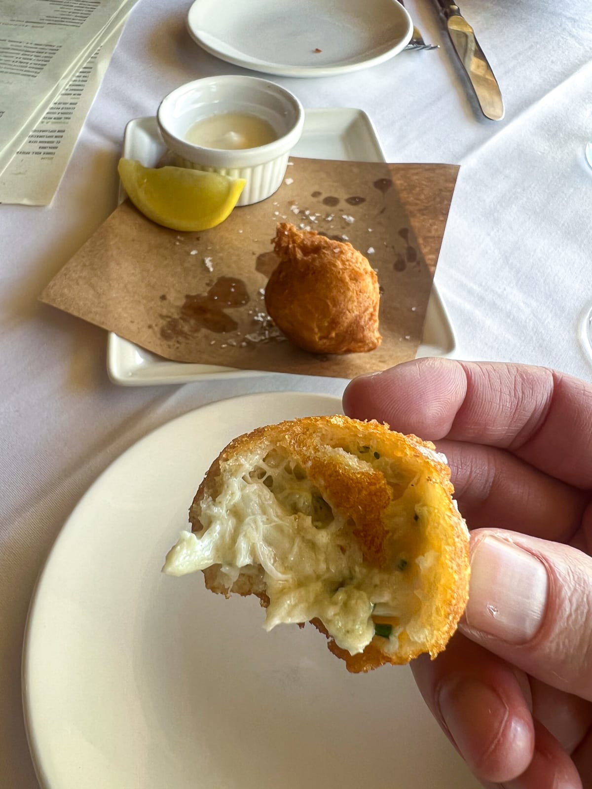 Biting into a signature blue crab beignet at La Petite Grocery