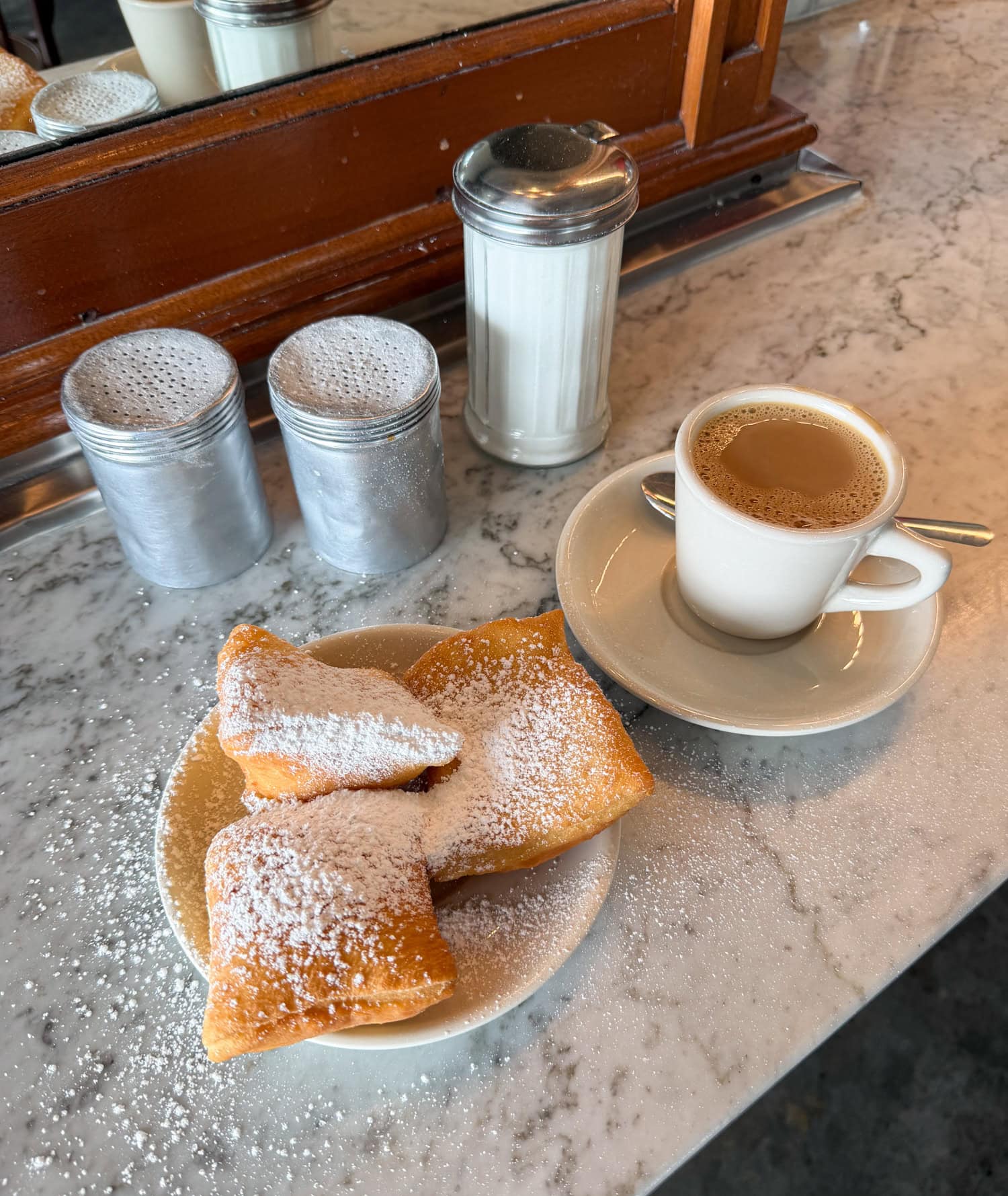 Three powdered sugar beignets with café au lait at Morning Call Coffee Stand in New Orleans.