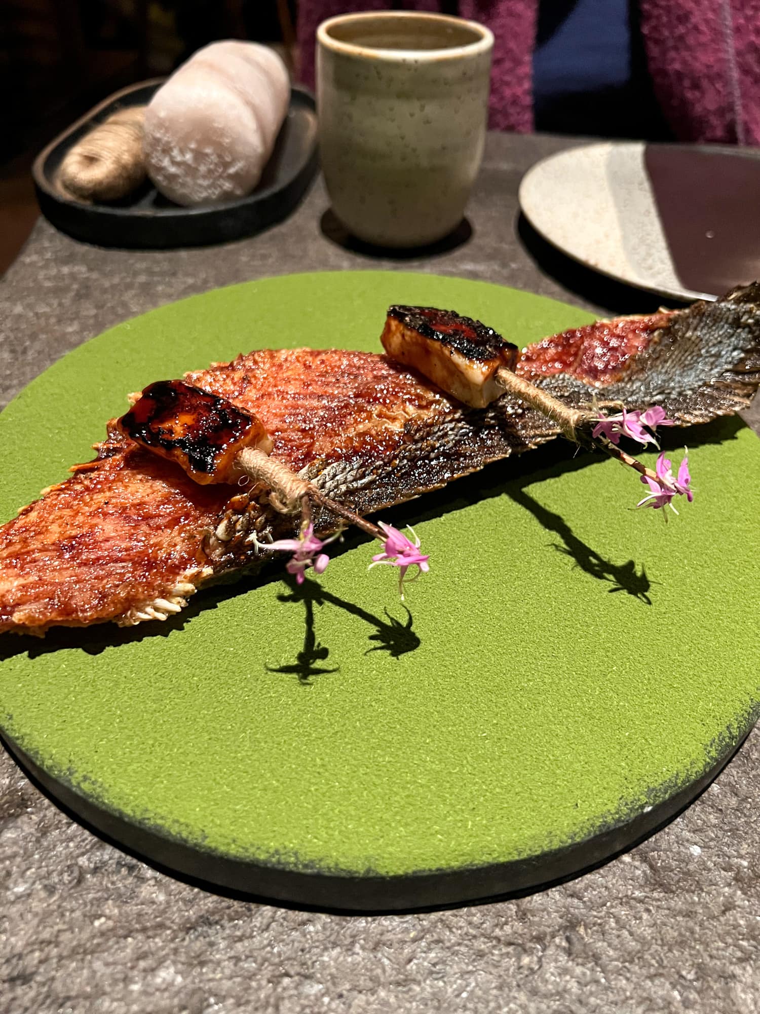 Paiche (Amazonian fish) with tucupi, charapita, and bellaco presented on matcha at Mayta Restaurante in Lima, Peru