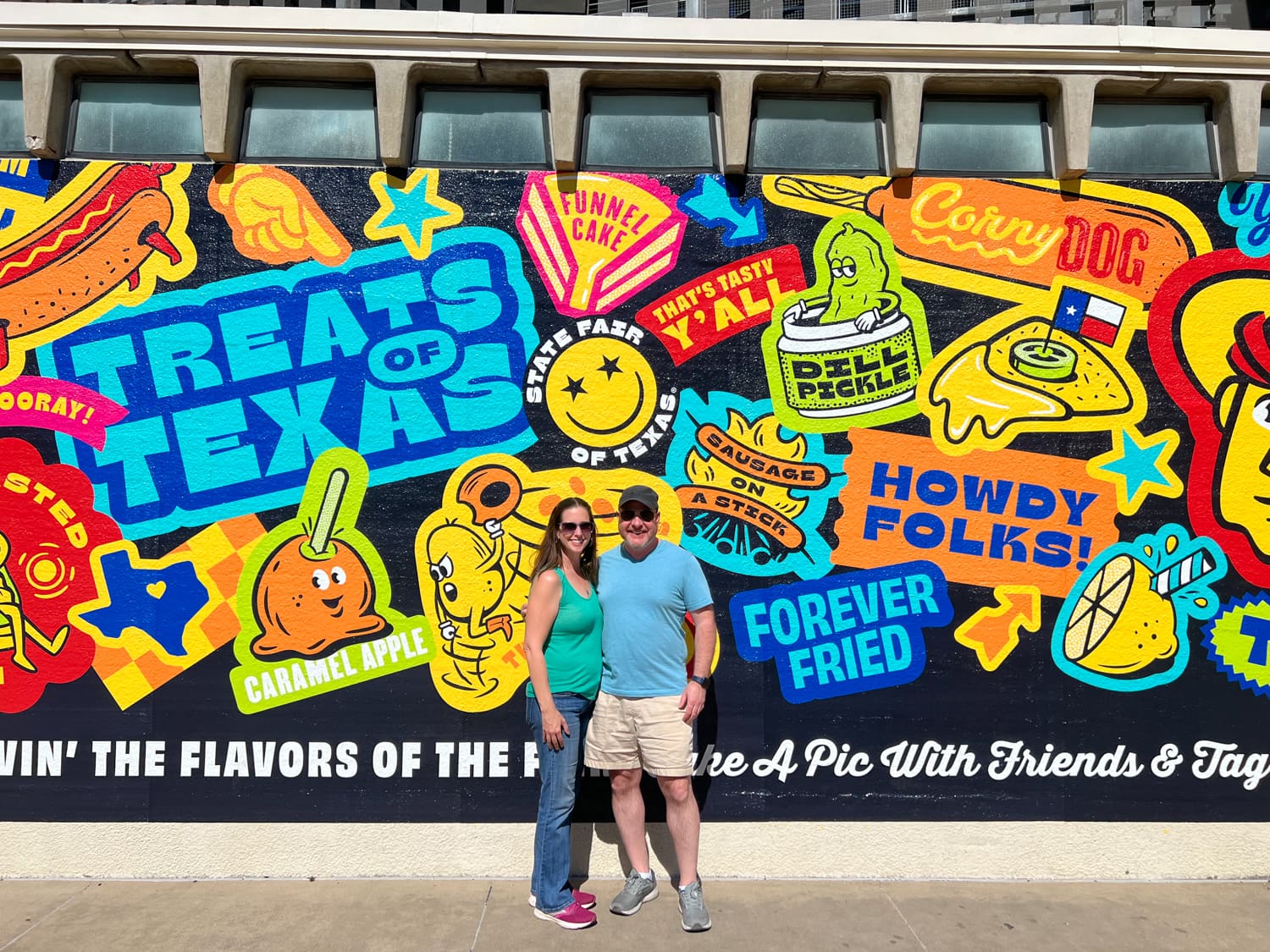 Kel and Dave in front of the "Treats of Texas" mural at the Texas State Fair 2022.