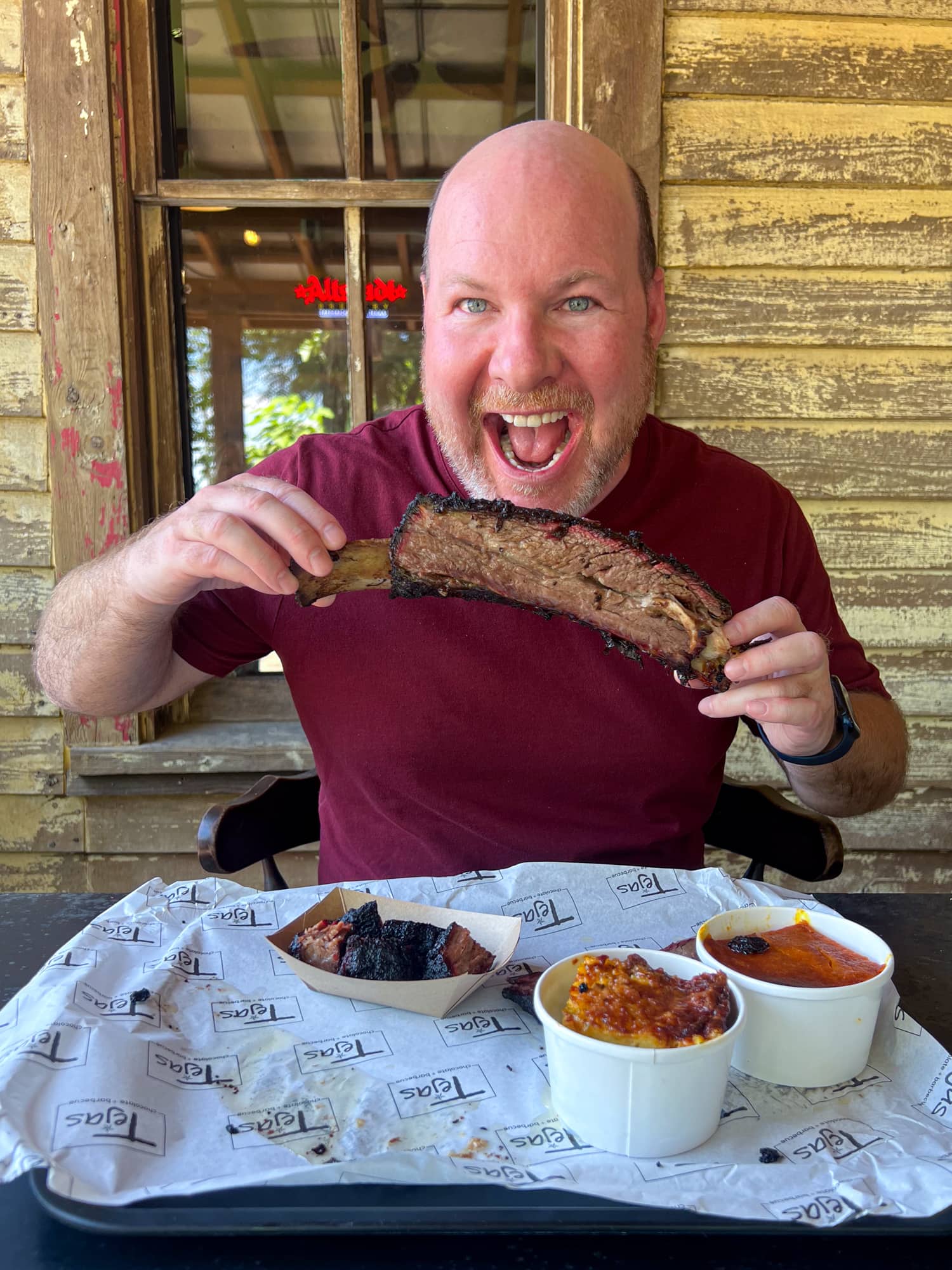 Dave about to bite a giant beef rib at Tejas chocolate + barbecue