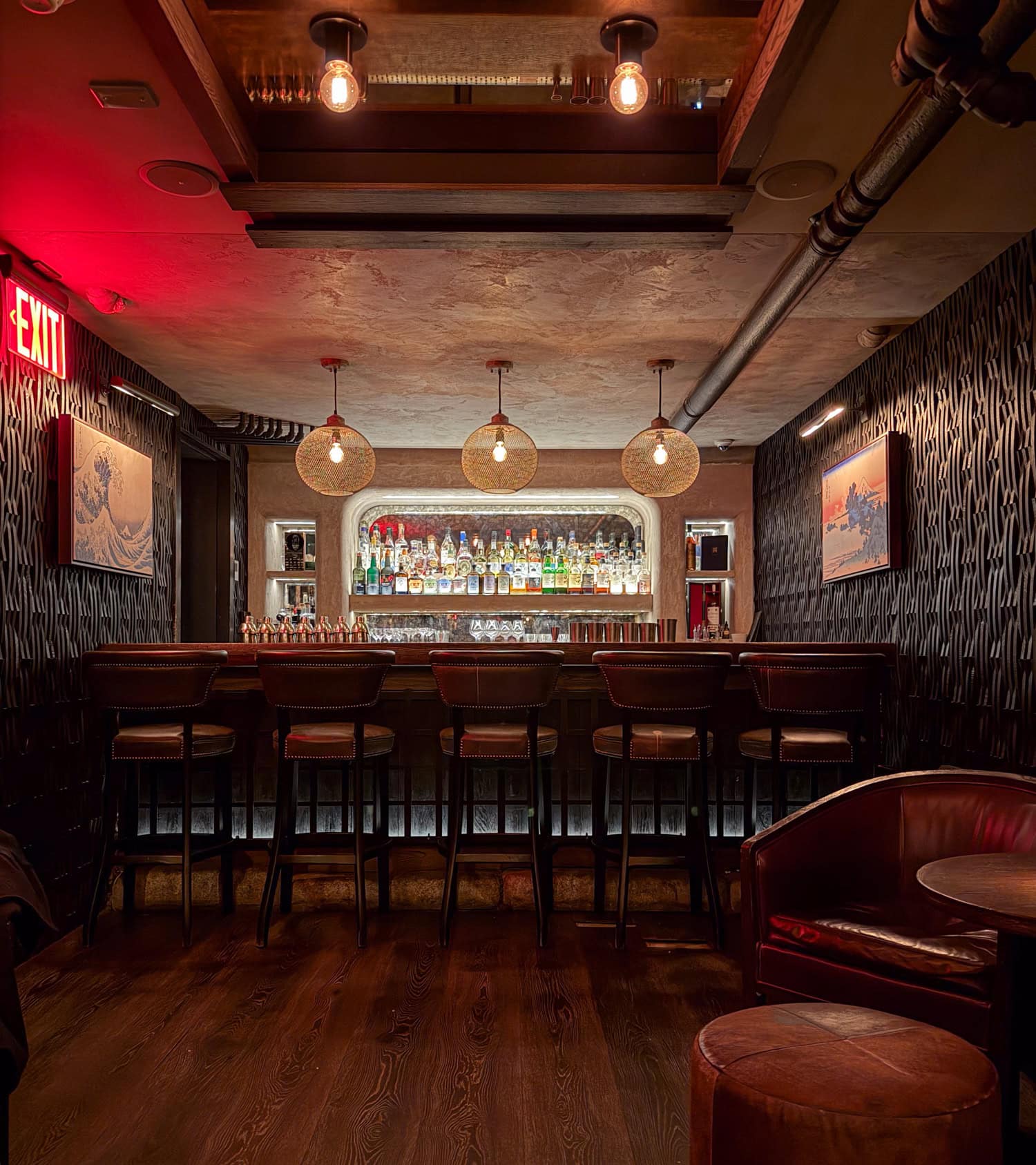 Dimly lit basement bar and leather seating inside Sip at Sip & Guzzle in New York City.