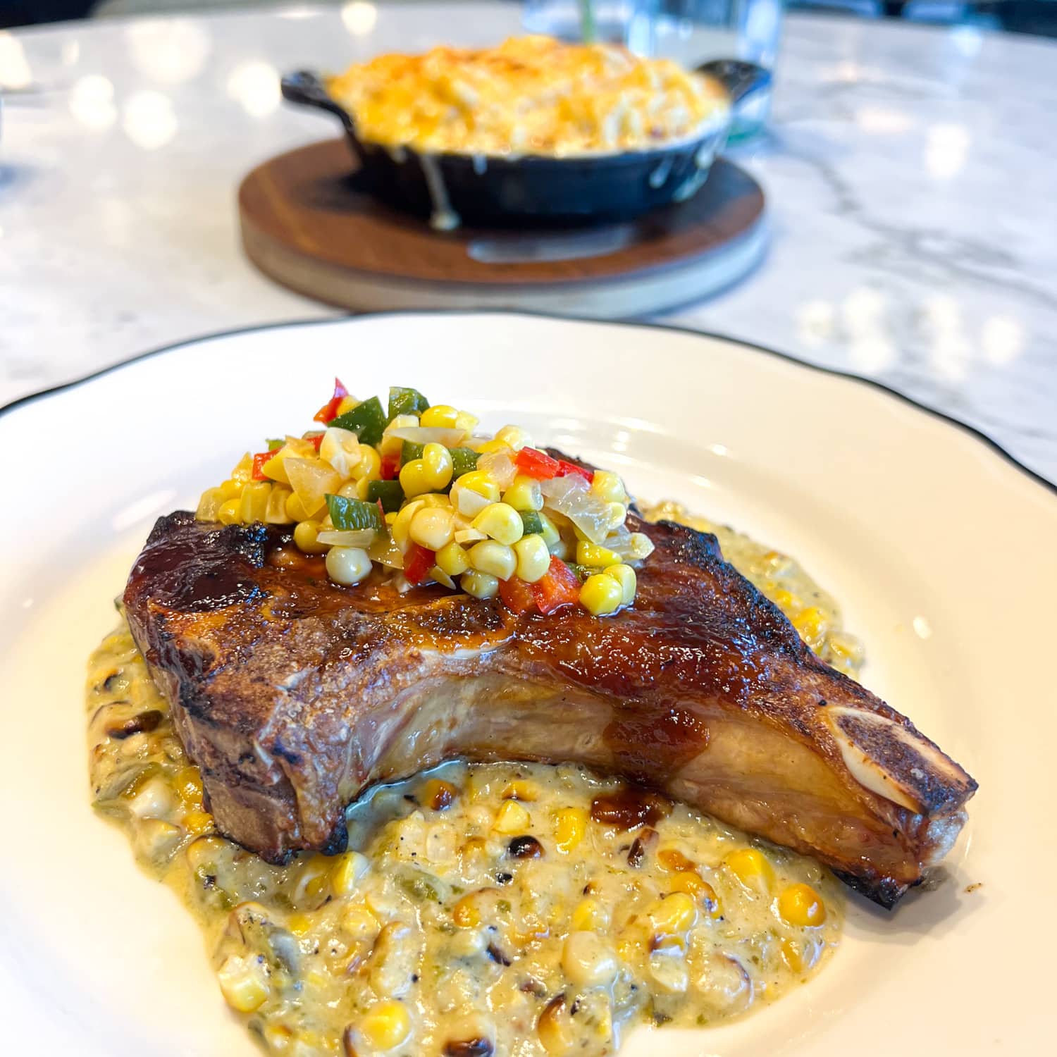 Grilled pork chop with poblano creamed corn, relish, and sweet bourbon glaze at The Brasserie at Hotel 1928, one of the best new restaurants in Waco, TX.