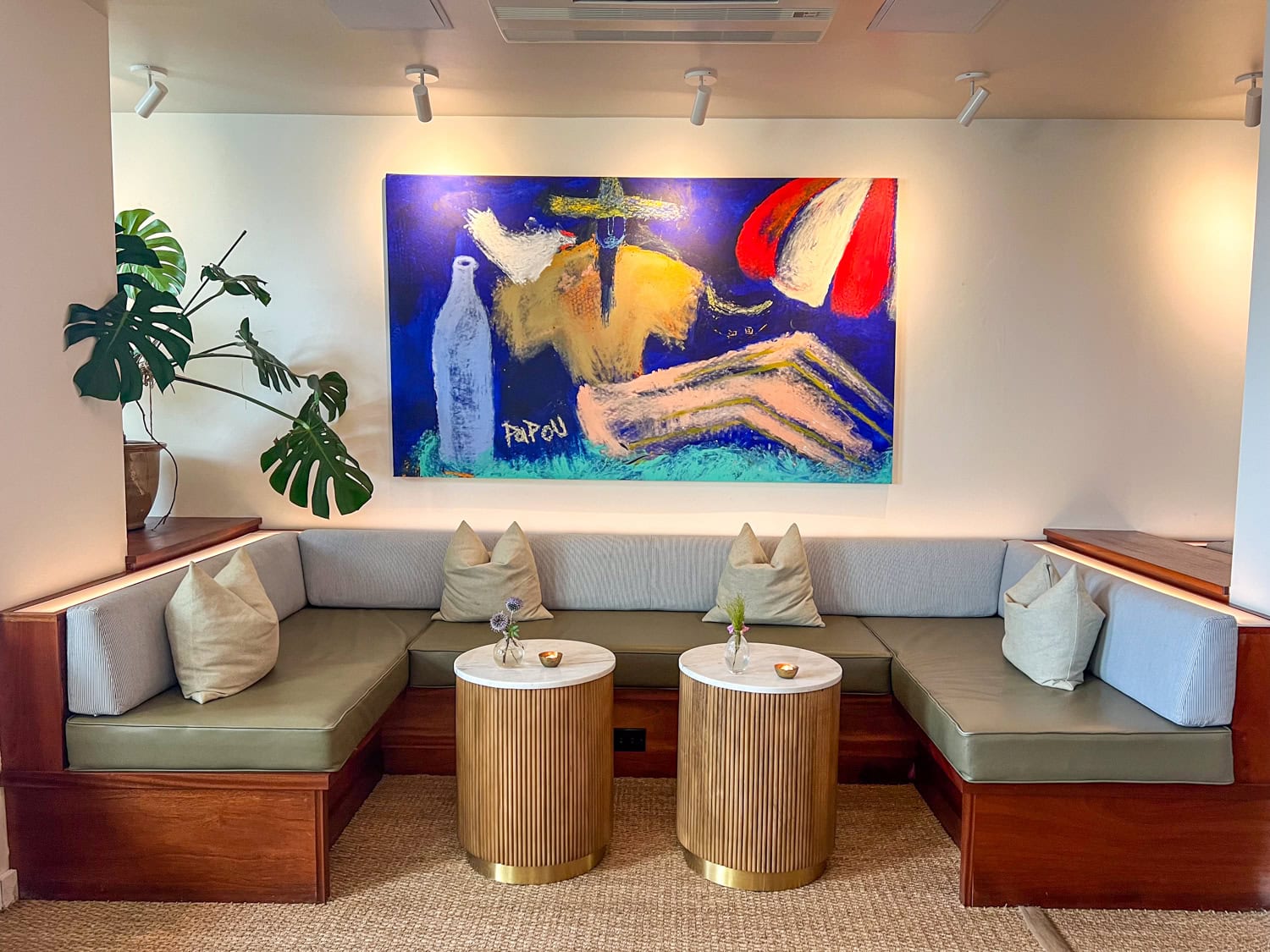 A seating area in The Den with a colorful painting by Papou Koliopoulos.