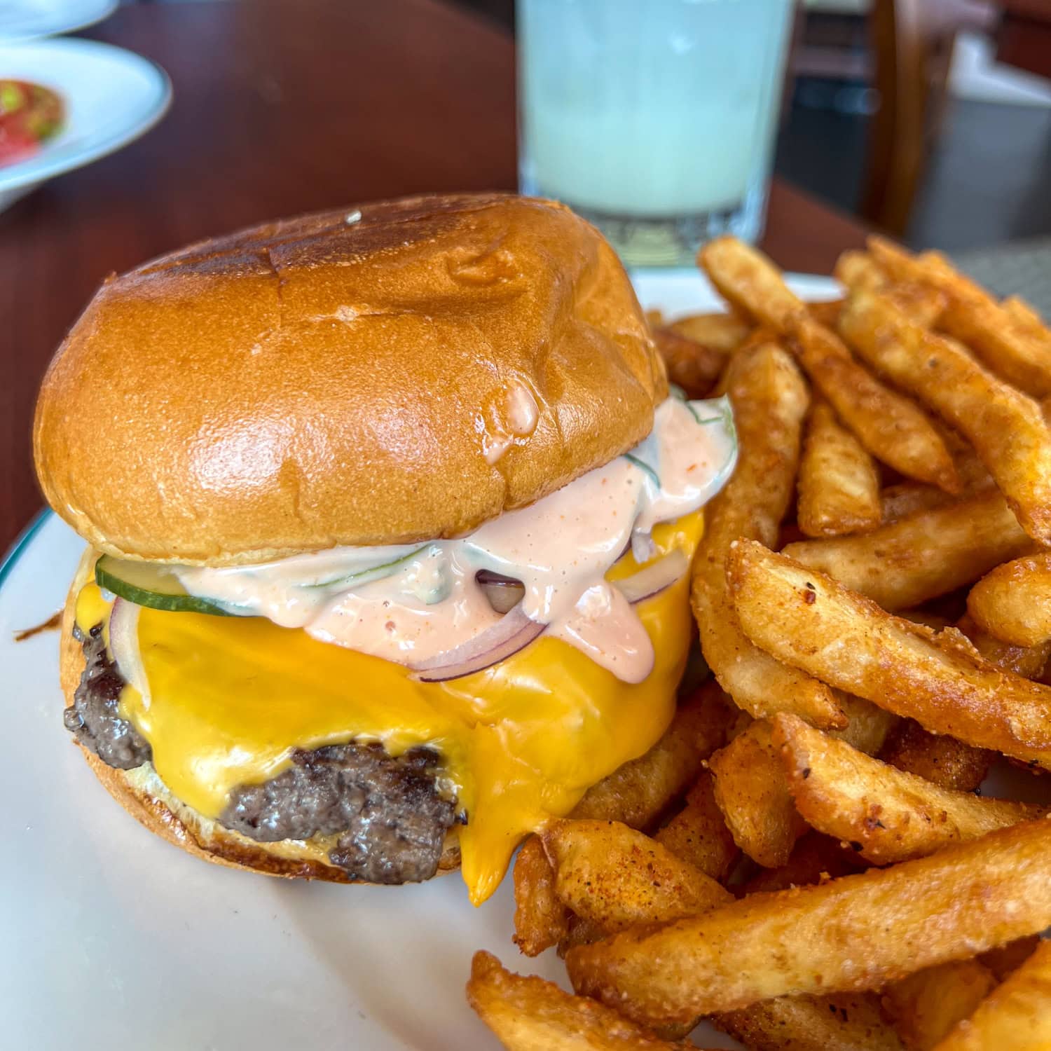 The Lucine cheeseburger with 44 Farms beef, cheddar, special sauce, pickles, and red onion, served with a side of French fries.