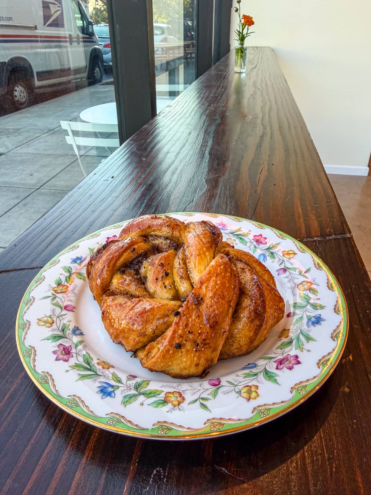 An orange blossom cardamom bun on a floral plate.