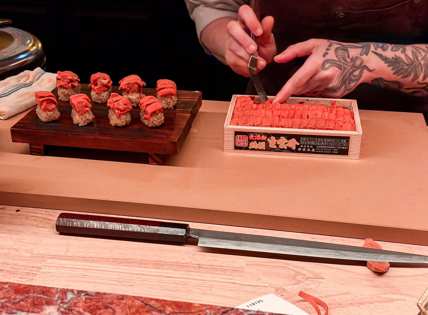 Chef Ambrely prepares uni nigiri at the counter beside her sushi knife at Anbā in New York City.