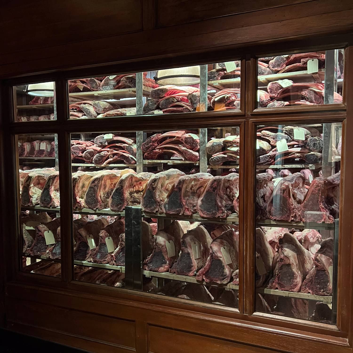 Dry-aged steaks aging behind glass at Gallaghers Steakhouse in New York City.