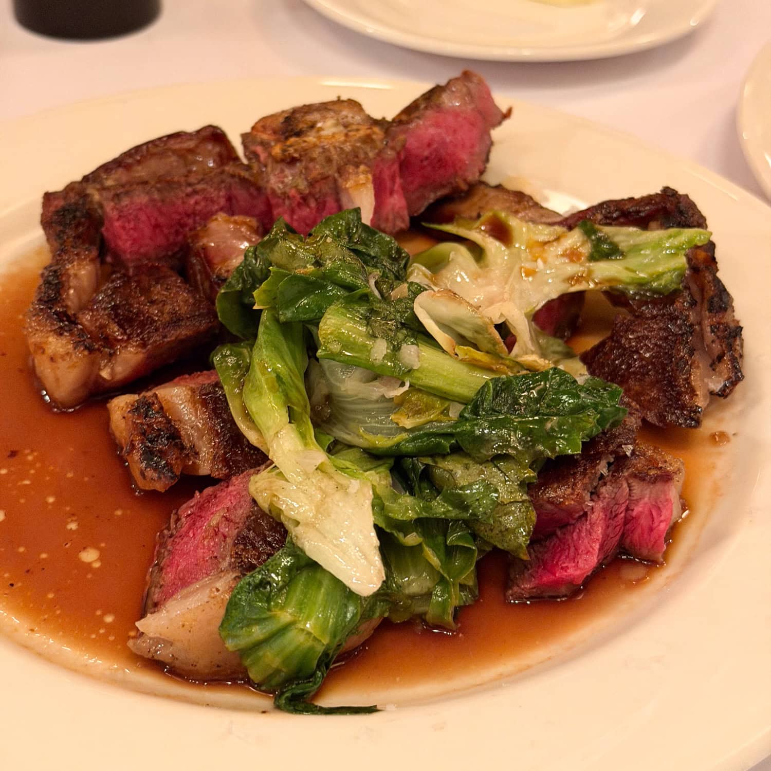 Sliced mutton chop with greens at Keens Steakhouse in New York City.