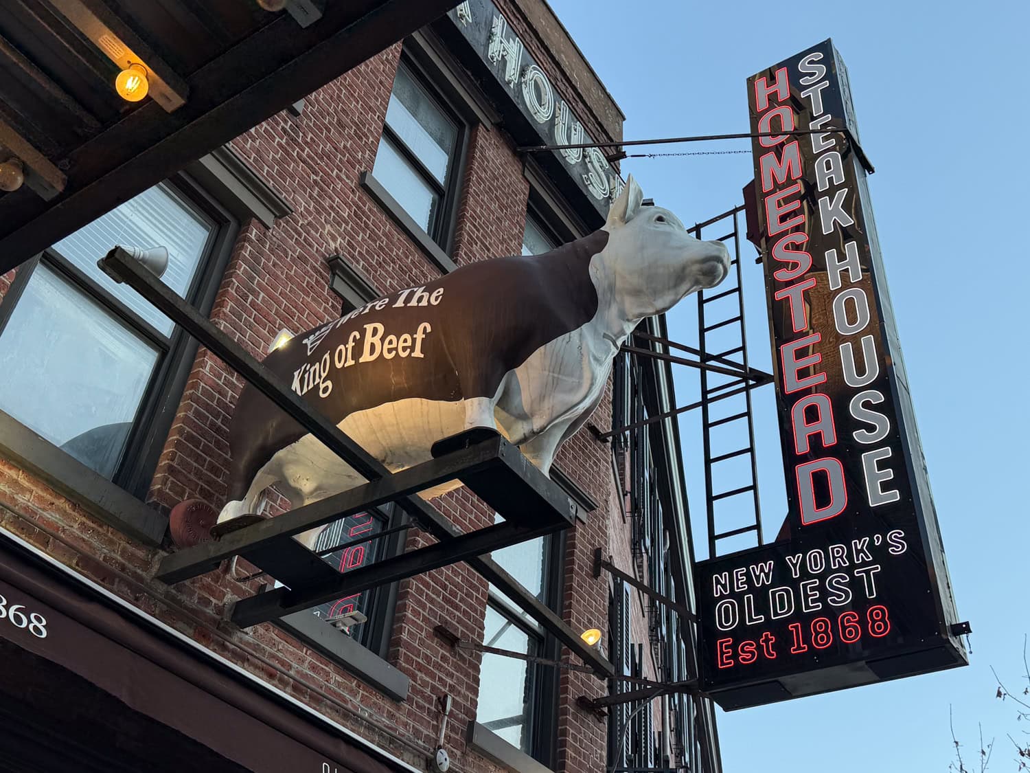 Exterior of Old Homestead Steakhouse with neon sign in New York City.