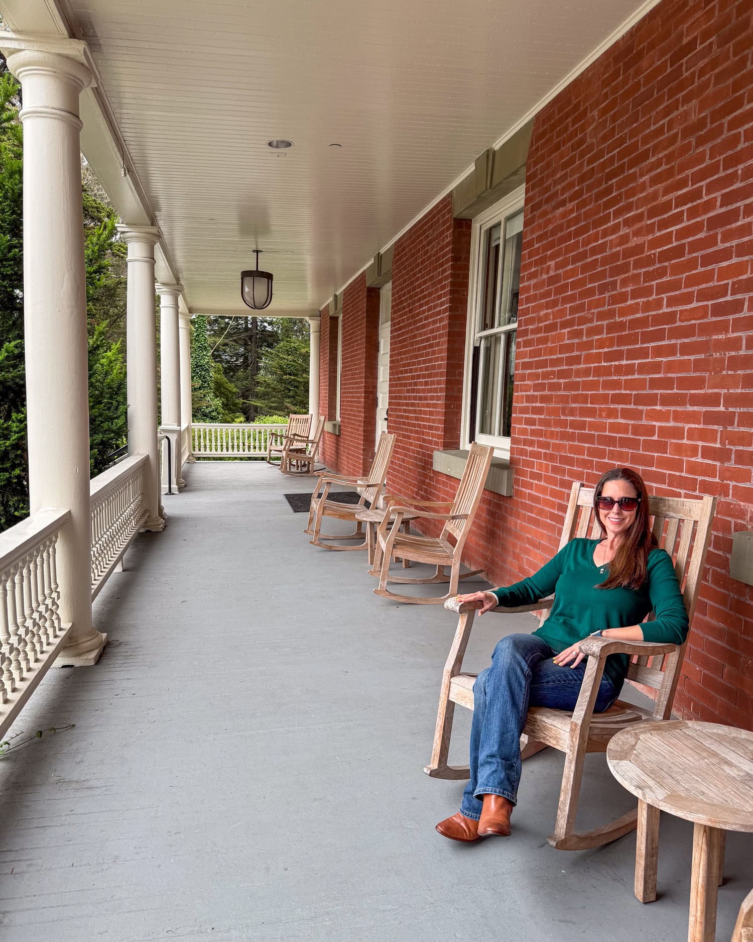 Kel seated in a wooden rocking chair on the porch at the Inn