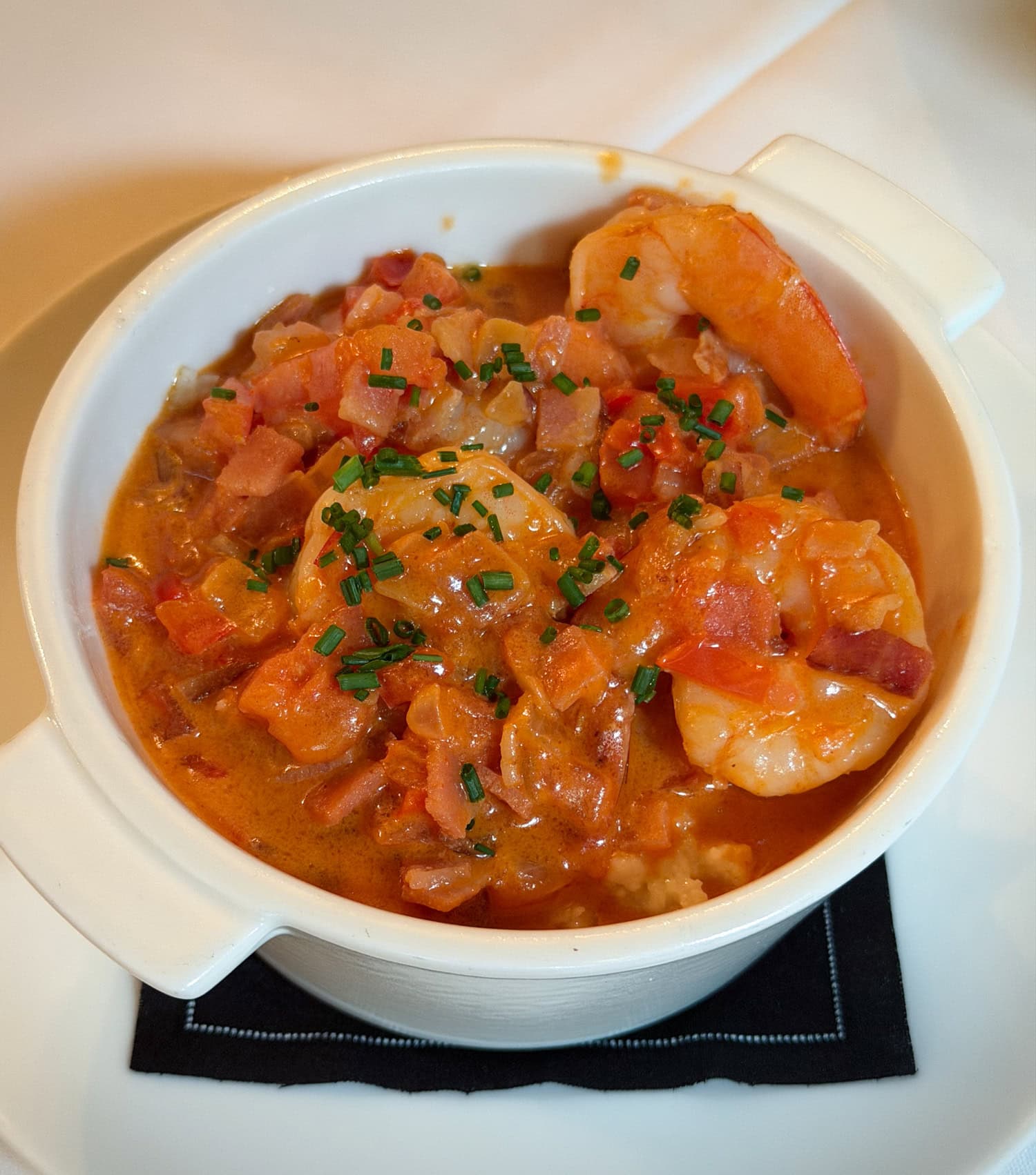 A bowl of shrimp and grits at Circa 1886 in Charleston, South Carolina, topped with sautéed shrimp, peppers, onions, tomatoes and bacon.