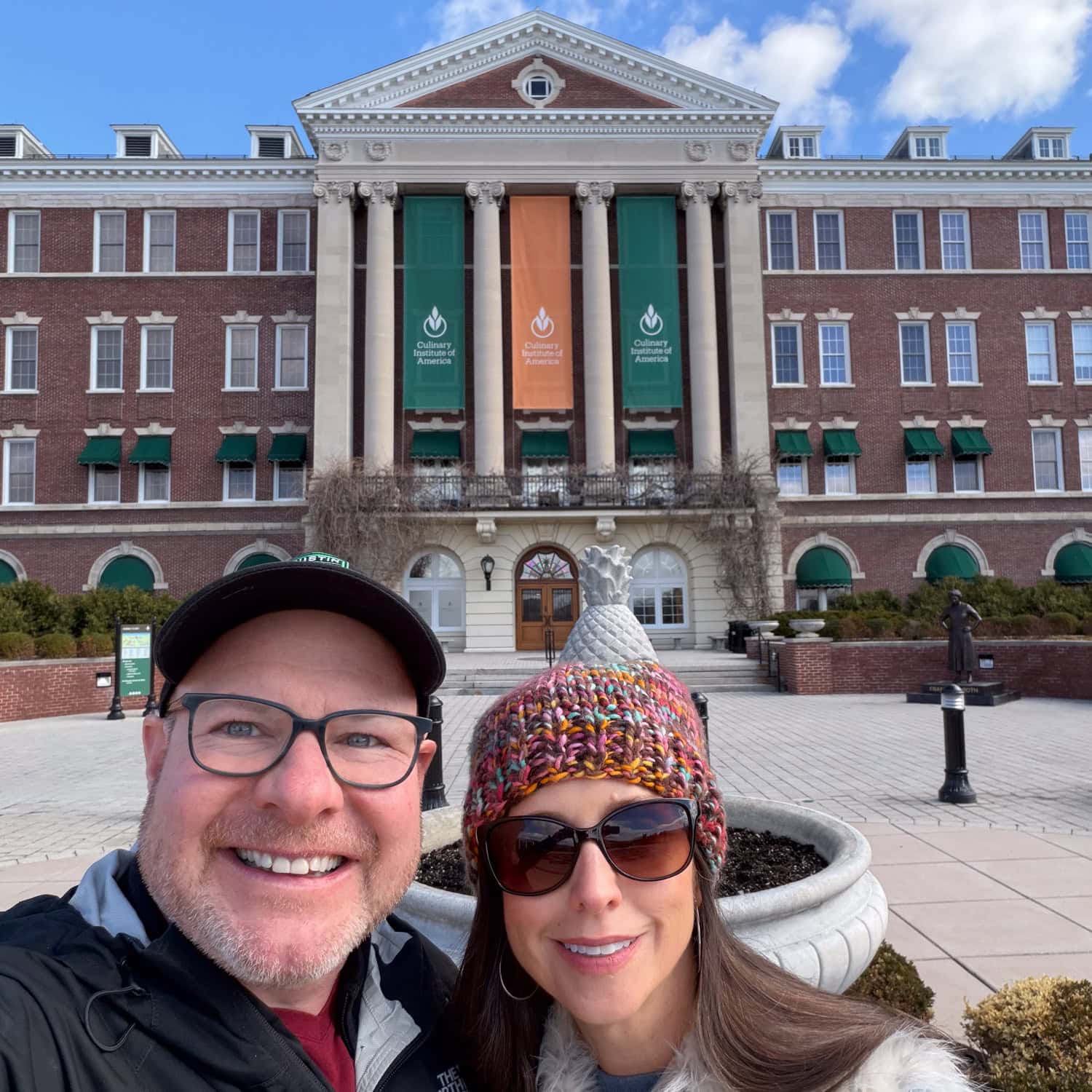 Dave and Kel taking a selfie in front of Roth Hall at the Culinary Institute of America.