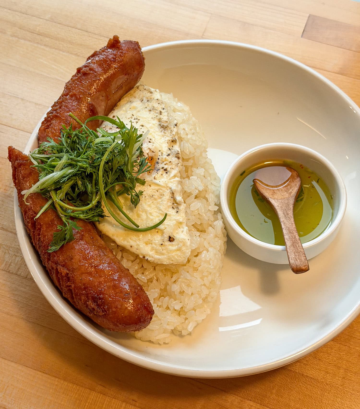 Hmong sausage links served with sticky rice, an over-easy egg, fresh herbs, and sweet-and-sour sauce at Diane's Place.