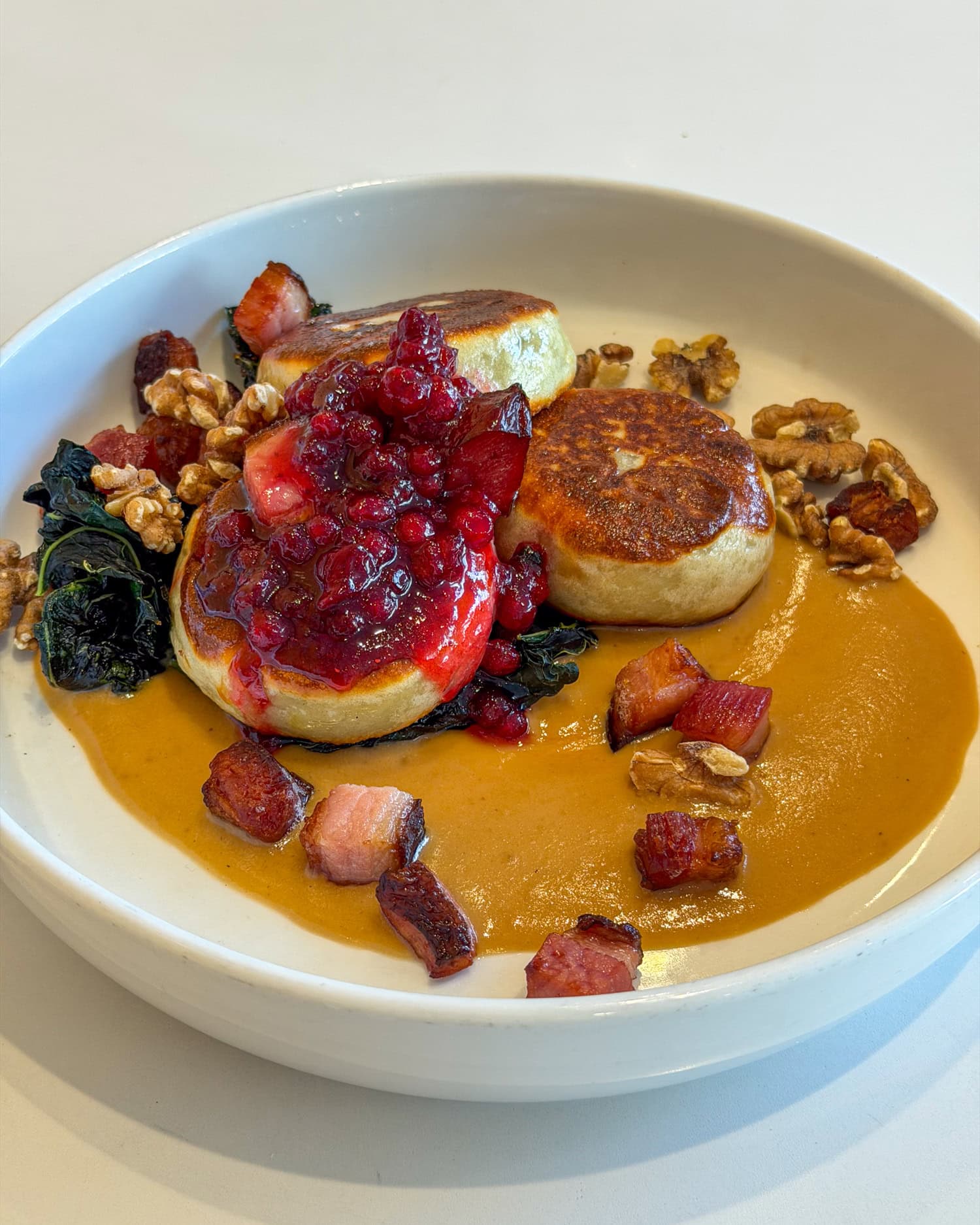 Kroppkakor potato dumplings with lingonberries, kale, walnuts and lardon at FIKA Café