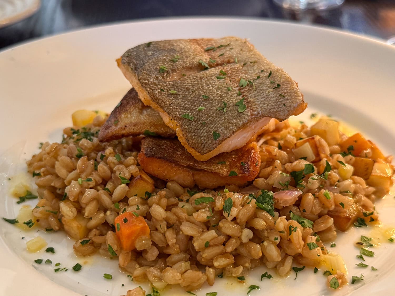Seared trout fillets served over farro and roasted root vegetables at American Bounty Restaurant.