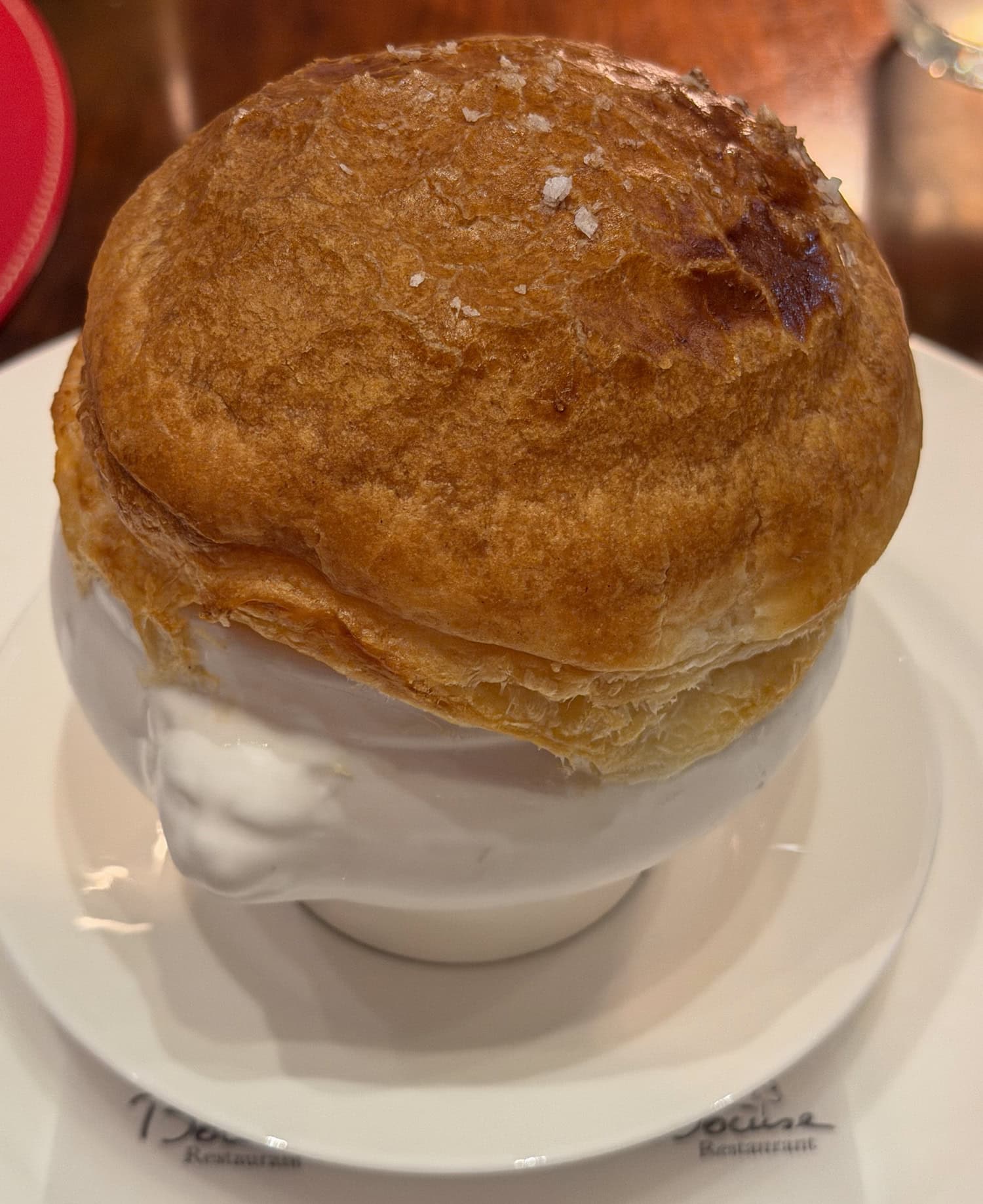 Truffle soup V.G.E. served in a white bowl sealed beneath a golden puff-pastry dome.
