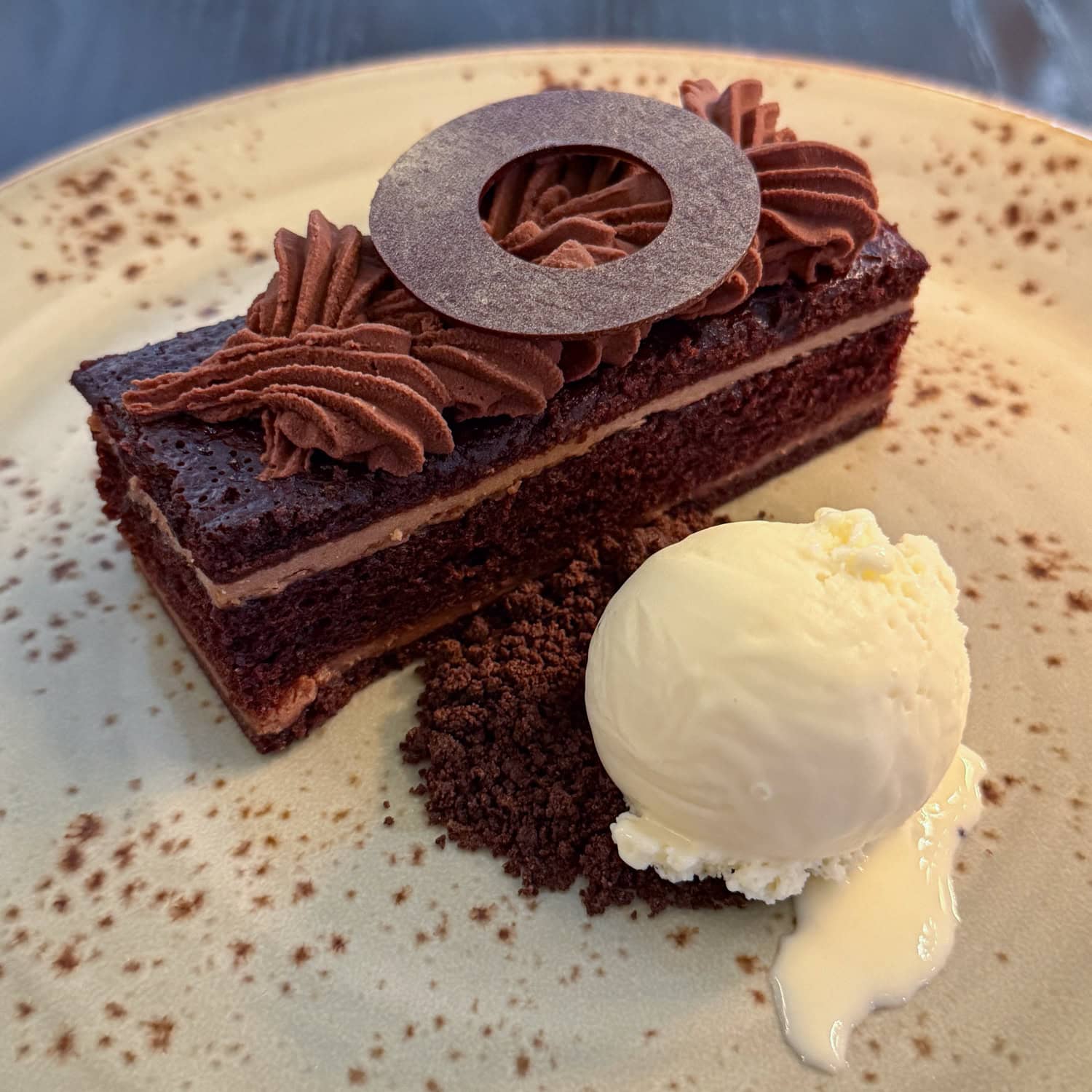 Layered whiskey chocolate cake with piped chocolate mousse, a chocolate disk, and a scoop of bourbon ice cream.