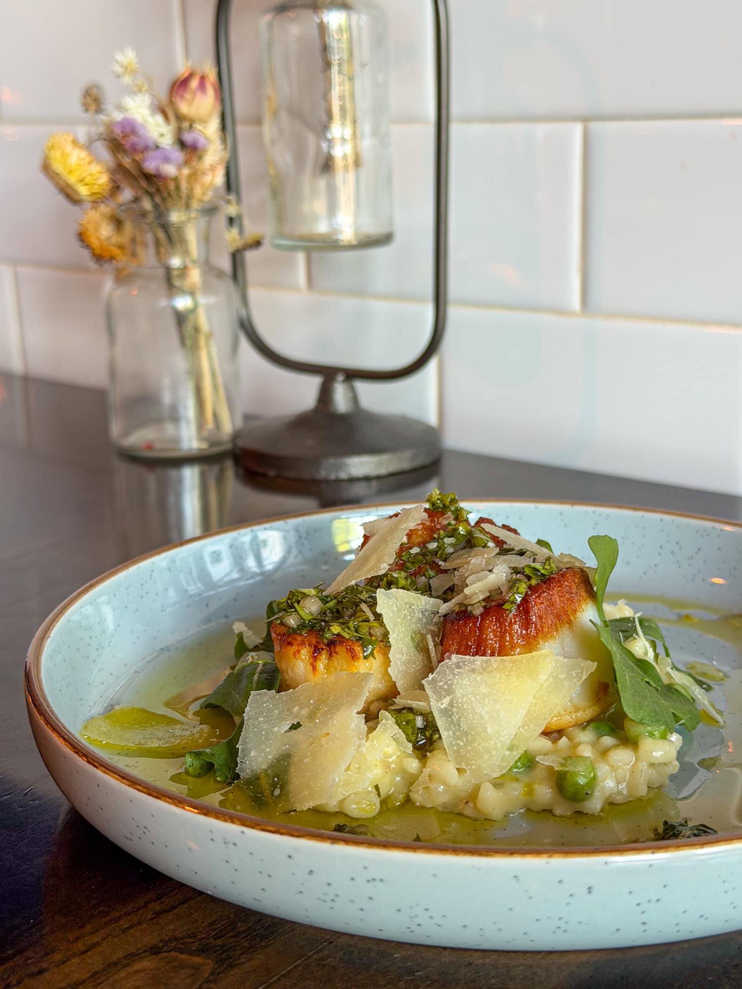 Seared scallops topped with shaved cheese and greens at Bar Purlieu in Eugene, OR.