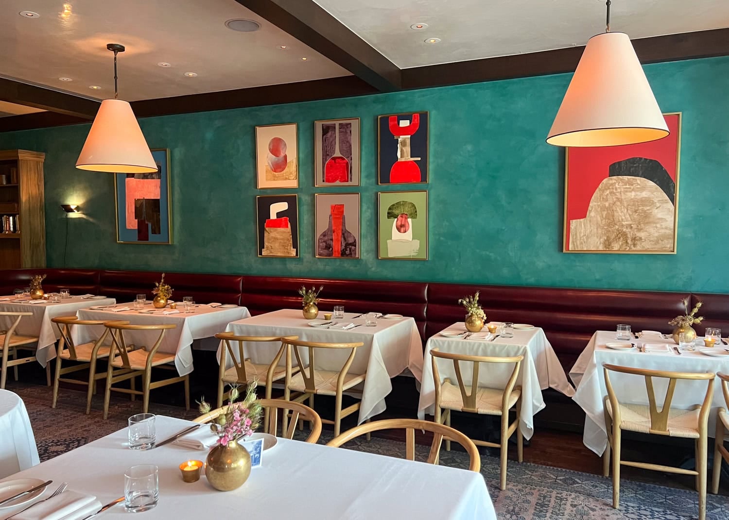 The dining room at Jeffrey's with teal walls and colorful abstract artwork.