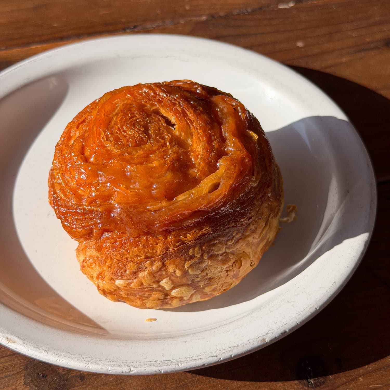 Orange-cardamom bun on a white plate at Sweet Life Patisserie.